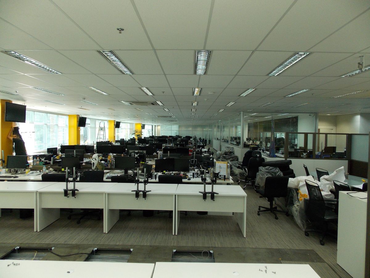 Escritório open space com caixas de piso para pontos de rede sob as mesas de trabalho