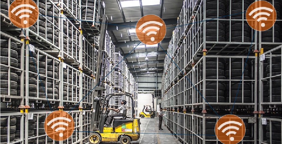 Corredor de armazém logístico com estanterias de grande altura, empilhadeira em operação e indicação de células de cobertura Wi-Fi — geometria que exige antenas direcionais orientadas no eixo do corredor em vez de access points omnidirecionais no teto