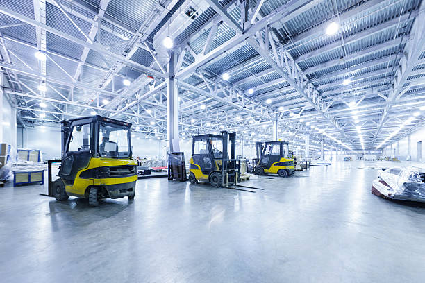Interior de galpão industrial de grande vão com trelliças metálicas expostas, pé-direito livre elevado, piso nivelado e frota de empilhadeiras — condição construtiva que define o comportamento da radiofrequência no interior da planta