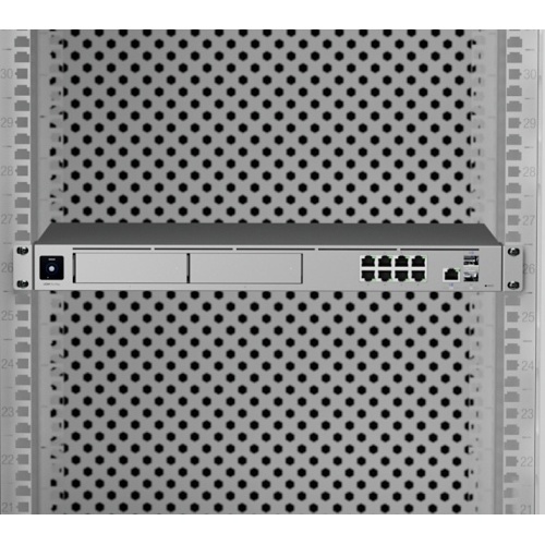 UniFi Dream Machine Pro Max montado em rack de 19 polegadas ocupando 1U, com as duas baias frontais de armazenamento para gravação de CFTV, portas de rede e interfaces SFP+ visíveis